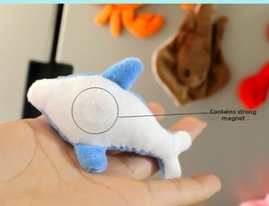 Detail of blue plush dolphin fridge magnet with built-in strong magnet held in hand