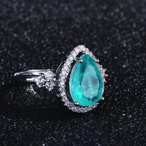 Macro shot of a teardrop-shaped green gemstone ring with sparkling diamond halo settings
