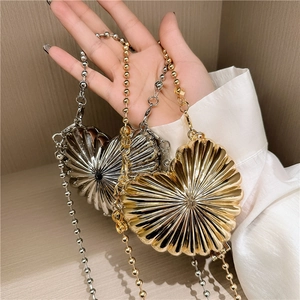 Mini heart-shaped metal clutch bag with radial ribs and beaded chain strap in gold and silver