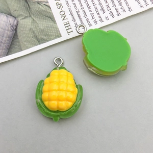 Detail shot of artificial corn resin charms in yellow and green with metal hanging loops