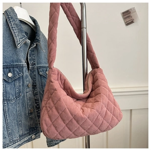 Pink quilted corduroy tote bag hanging on a metal hanger next to a blue denim jacket