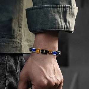 Detail of 10mm tiger eye beaded bracelet with a golden letter A on a black cylindrical bead