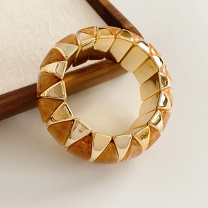 Detailed close-up of geometric gold metal and amber resin elastic bracelet links