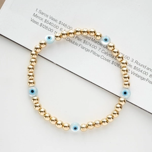 Detail of 18K gold-plated beaded elastic bracelet with five light blue evil eye charms