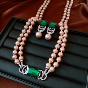 Detail of pink double-layer pearl necklace and earrings with green square gemstones