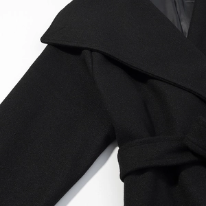 Close-up of wide lapel design and waist tie detail on black wool blend coat