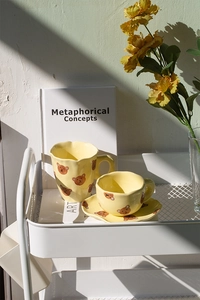 Close-up of yellow ceramic coffee cup and saucer set with cute hand-painted bear design