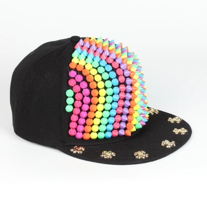 Detailansicht einer schwarzen Hip-Hop-Cap mit Regenbogen-Spikes und goldenen Nieten.