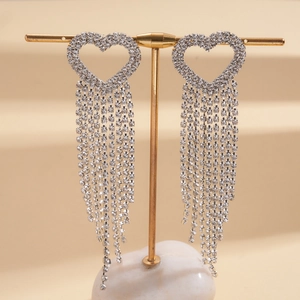 Macro shot of silver heart tassel earrings with sparkling rhinestones on golden stand