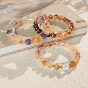 Detail of beaded bracelets with amethyst, tiger eye, and citrine on a beige background