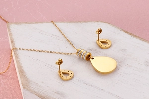 Detailed view of teardrop necklace and earrings set with crystal inlay on wooden board