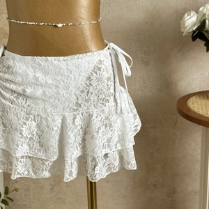 Close-up of white floral lace mini skirt with tiered ruffles and waist drawstring