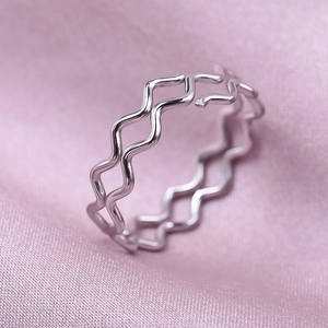 Detail of silver wavy double-layer open ring on pink silk background for a minimalist look