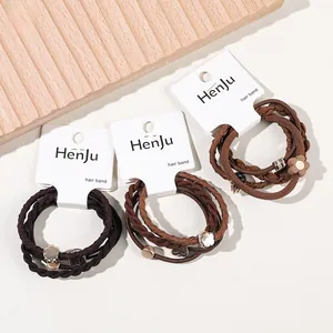 Three sets of brown elastic hair bands with metal heart and flower charms on a card