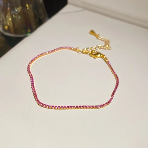 Close-up of a gold tennis bracelet featuring sparkling pink zircons with an adjustable chain