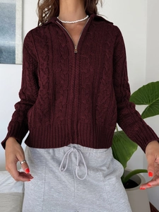 Detail of dark red cable knit cardigan with zipper closure and textured pattern