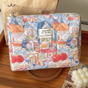Detailed view of quilted makeup bag with hand-drawn cartoon prints and fabric label