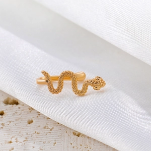 Detailed view of a golden snake-shaped non-piercing nose clip on a textured stone surface