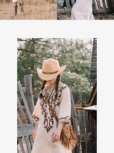 Detail of bohemian ivory dress with brown embroidery and western cowboy hat for summer travel