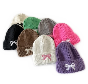 Detailed close-up of multi-colored knitted hats featuring delicate bow embroidery accents