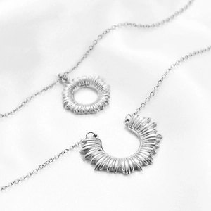 Detailed view of silver layered necklaces with textured sun and moon pendants on silk