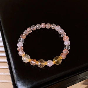 Detail of citrine beaded bracelet with gold spacers on black leather background