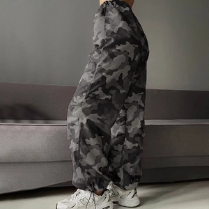 Dettaglio dei pantaloni cargo mimetici con polsini elastici indossati su un divano