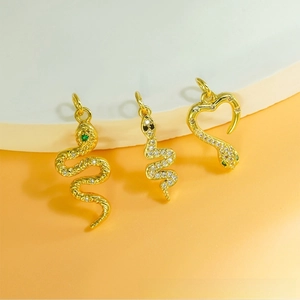 Detailed view of three gold snake pendants with cubic zirconia and green gemstone eyes