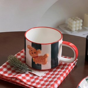 Close-up of ceramic mug with vertical black stripes and a 3D teddy bear relief detail