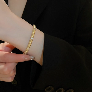 Detailed view of gold plated zircon bracelet with brushed texture on black suit cuff
