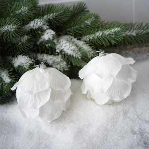 Macro view of white petal Christmas balls with glitter on snow covered pine branches