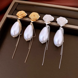 Detail of rose pearl earrings featuring gold and silver finishes with elegant fringe
