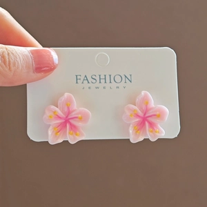 Detailed close-up of pink cherry blossom earrings with glossy translucent petals