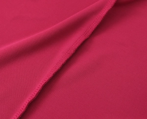 Dettaglio ravvicinato delle cuciture overlock su un abito lungo in maglia magenta