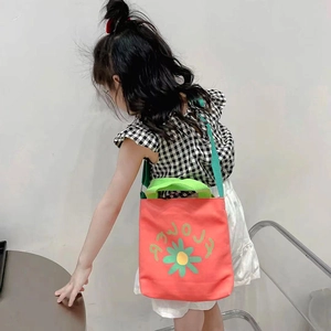 Girl wearing a coral pink canvas handbag with green straps and cute yellow flower print