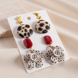 Close-up of leopard print and polka dot flower earrings on display card with stone