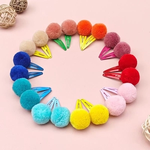 Colorful plush pompom hair clips set in rainbow colors arranged in a creative circle
