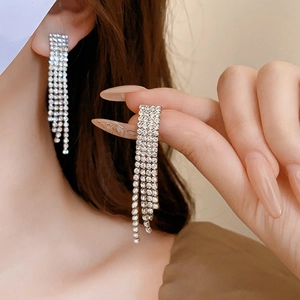 Close-up of sparkling rhinestone tassel earrings in silver finish on a female model