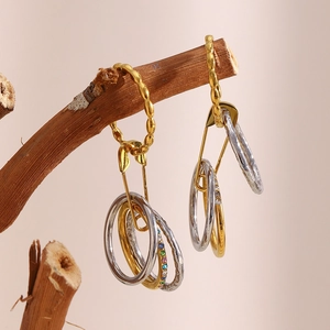 Artistic close-up of safety pin ring with colorful stones on natural wood branch