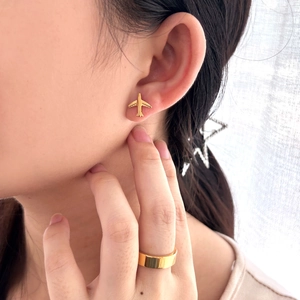 Minimalist 18K gold-plated airplane stud earrings worn by a model with a matching gold ring
