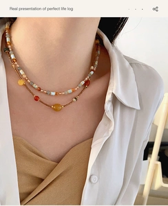 Close-up of double-layer beaded necklace with agate stones on model in warm studio lighting