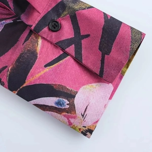 Dettaglio del polsino della camicia fucsia con stampa floreale nera e bottone nero