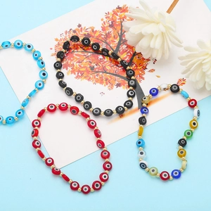 Dettaglio di braccialetti di perle colorate Evil Eye con distanziatori dorati su sfondo blu