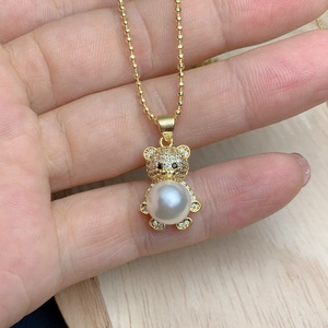 Close-up of golden bear pendant with zircon head and large pearl belly on a chain