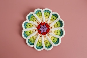 Detailed close-up of handmade crochet flower coasters in vibrant gradient yarn colors