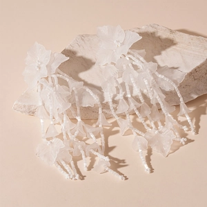 Detail of white matte acrylic flower earrings with beaded tassels on natural stone