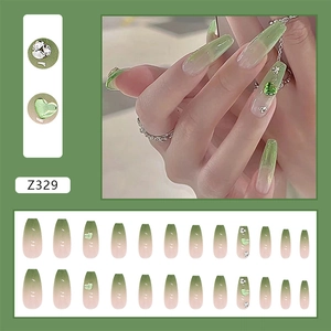 Detailed view of long coffin press-on nails with green heart charms and floral accents