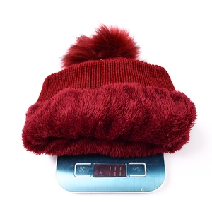 Detail showing red cable knit beanie with faux fur pom and plush thermal lining