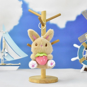 Detailed view of a cute plush rabbit keychain holding a soft pink strawberry charm
