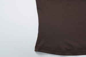 Gros plan de couture double aiguille sur l'ourlet de l'ensemble tricoté marron